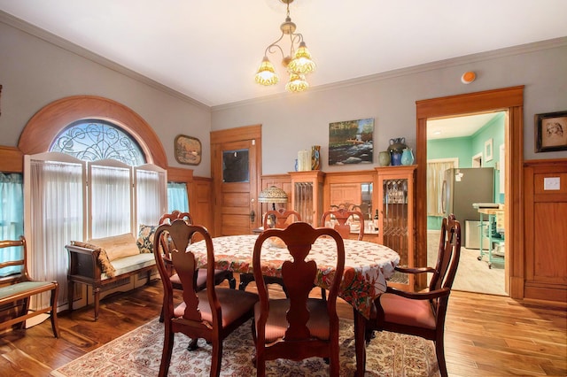 dining space featuring a chandelier, light wood-type flooring, and ornamental molding