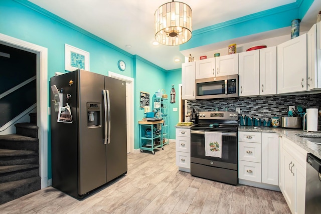 kitchen featuring hanging light fixtures, light wood-type flooring, appliances with stainless steel finishes, white cabinetry, and a chandelier