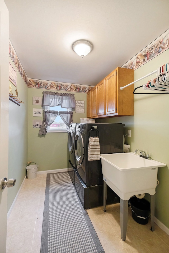 clothes washing area with light tile patterned flooring, cabinets, and washing machine and dryer