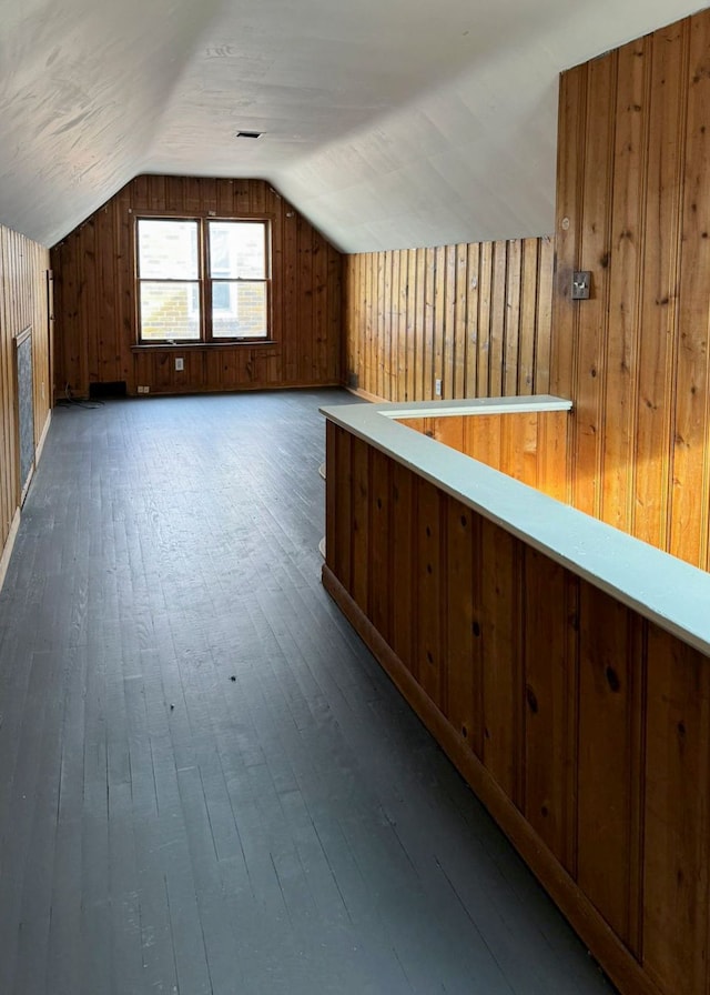 bonus room featuring dark hardwood / wood-style floors, wood walls, and lofted ceiling