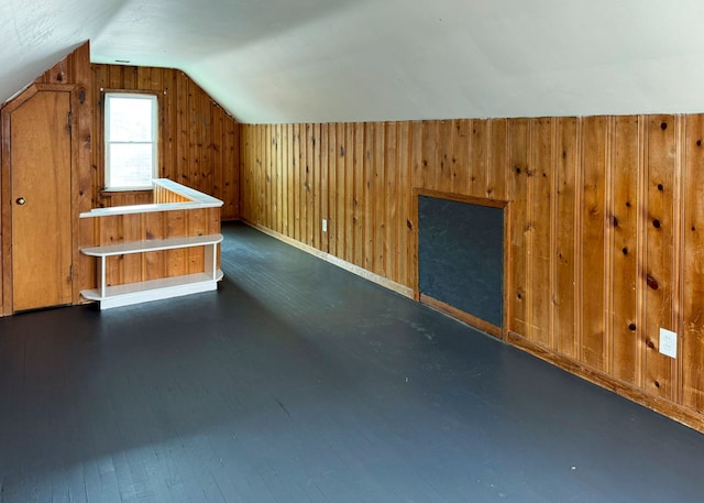 additional living space featuring wood walls and vaulted ceiling