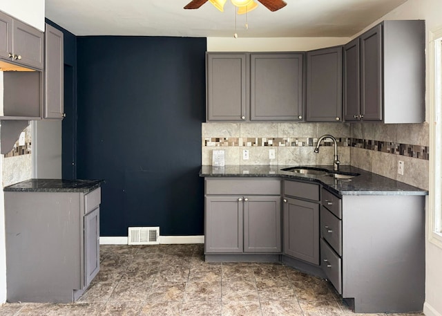 kitchen featuring gray cabinetry, decorative backsplash, ceiling fan, and sink