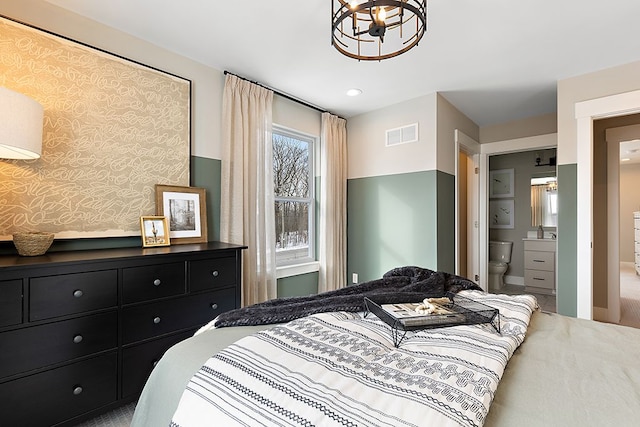 carpeted bedroom with a notable chandelier and connected bathroom