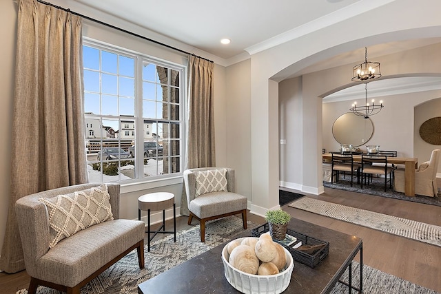 sitting room featuring ornamental molding, wood-type flooring, and a notable chandelier