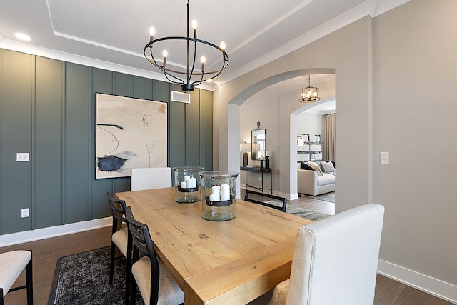 dining room with hardwood / wood-style flooring, a tray ceiling, and a notable chandelier