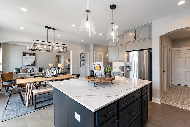 kitchen featuring hardwood / wood-style floors, gray cabinetry, a center island, pendant lighting, and stainless steel fridge with ice dispenser