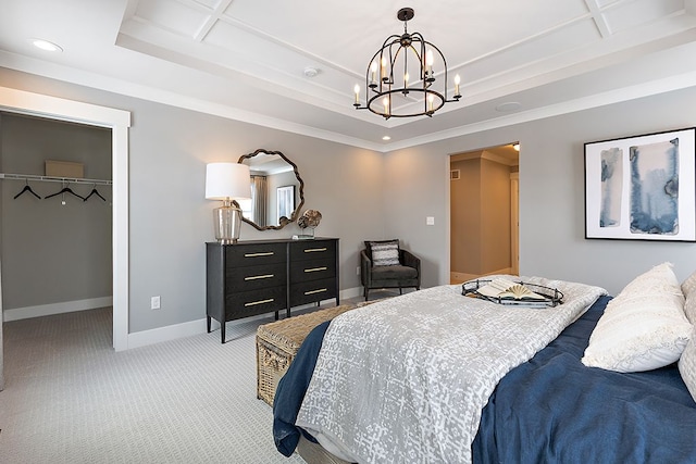 bedroom with light carpet, a tray ceiling, a spacious closet, a chandelier, and a closet