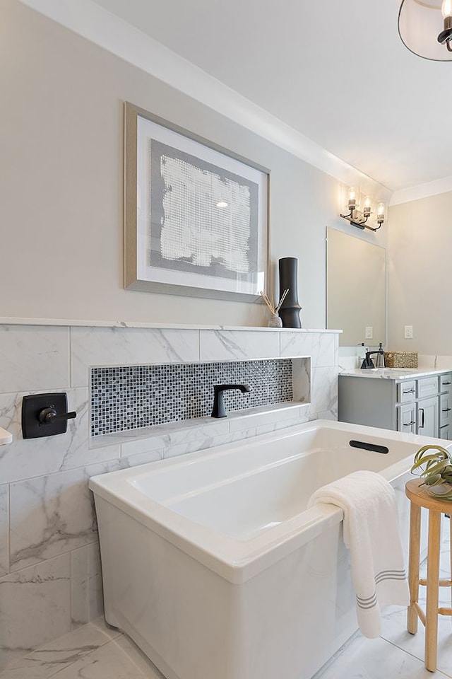 bathroom featuring vanity, an inviting chandelier, ornamental molding, tile walls, and a tub to relax in