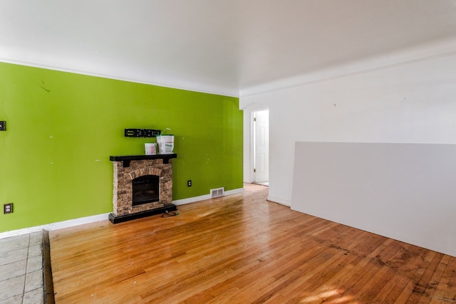 unfurnished living room with a stone fireplace and wood-type flooring