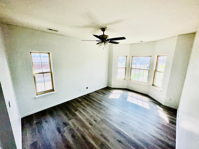 spare room with a textured ceiling, dark wood-type flooring, ceiling fan, and a healthy amount of sunlight