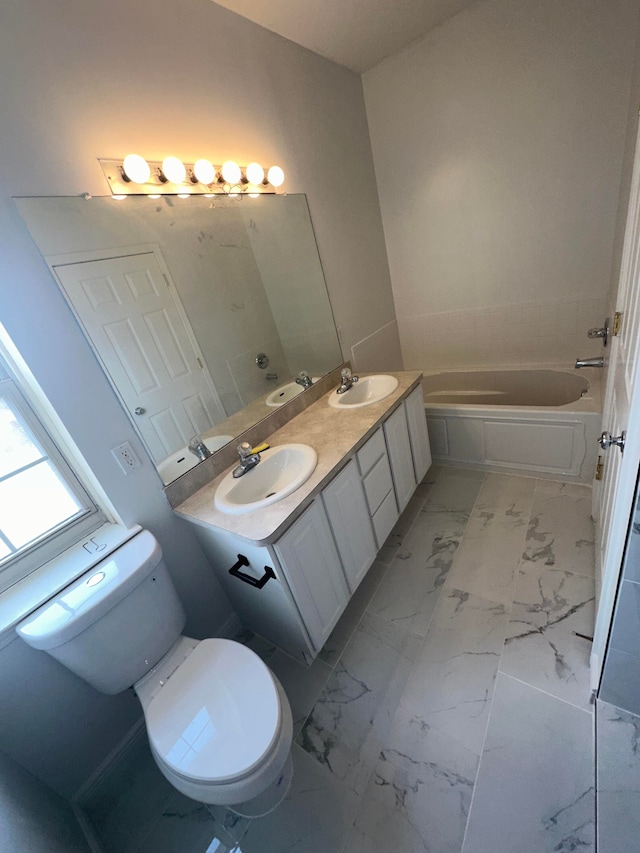 bathroom featuring a washtub, vanity, and toilet