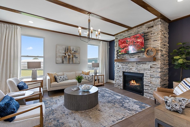 living room with dark hardwood / wood-style flooring, ornamental molding, an inviting chandelier, beamed ceiling, and a stone fireplace