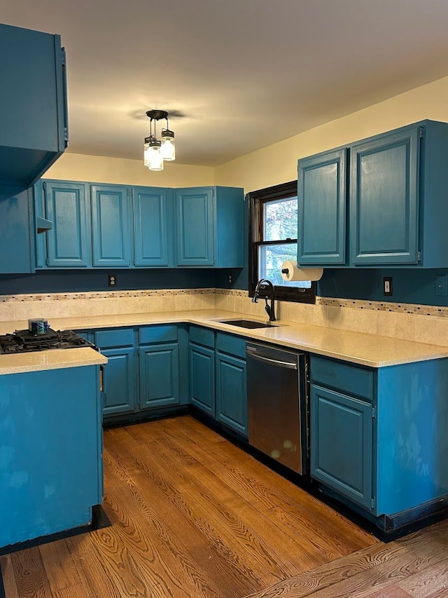 kitchen featuring hardwood / wood-style floors, stainless steel dishwasher, blue cabinets, and sink