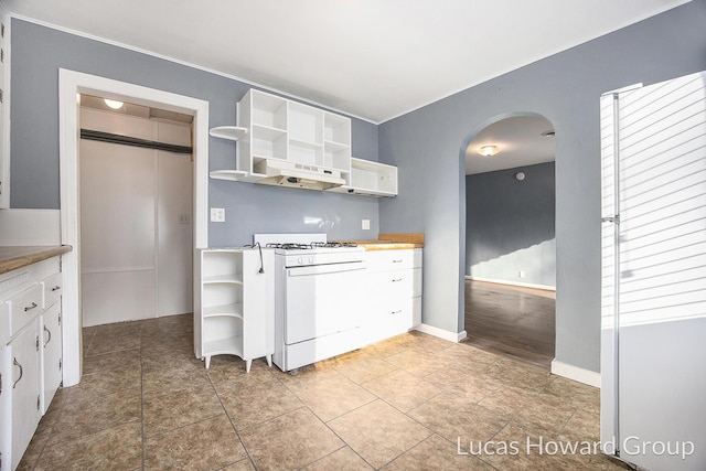 kitchen featuring tile patterned floors, white gas range, and white cabinets