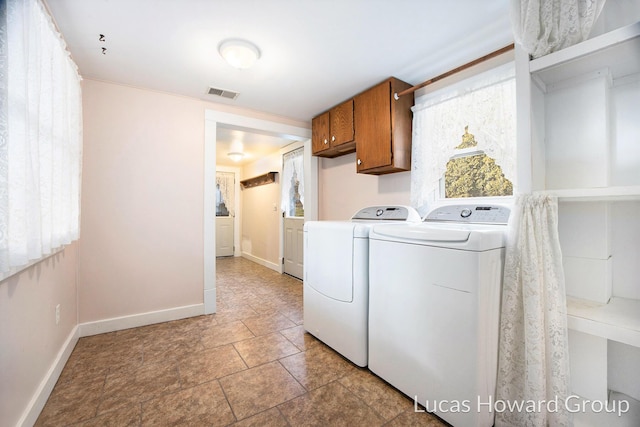 clothes washing area with separate washer and dryer and cabinets