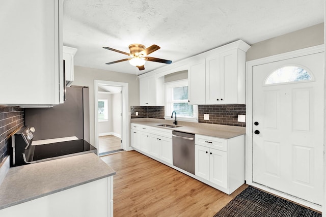 kitchen with sink, stainless steel appliances, white cabinetry, and light hardwood / wood-style flooring