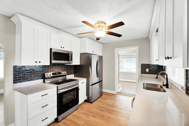 kitchen featuring white cabinetry, sink, light hardwood / wood-style flooring, a textured ceiling, and appliances with stainless steel finishes