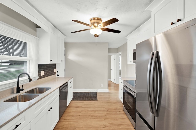 kitchen featuring sink, white cabinets, stainless steel appliances, and light hardwood / wood-style flooring