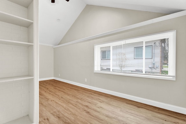 unfurnished room featuring built in shelves, ceiling fan, wood-type flooring, and vaulted ceiling