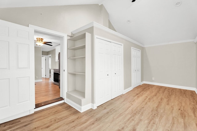 interior space with lofted ceiling, ceiling fan, ornamental molding, light hardwood / wood-style floors, and multiple closets