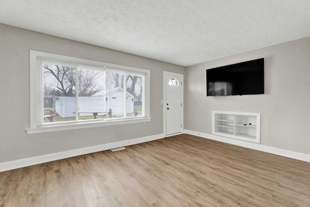 unfurnished living room with plenty of natural light, hardwood / wood-style floors, and a textured ceiling