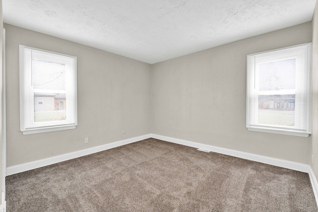 carpeted empty room featuring a textured ceiling