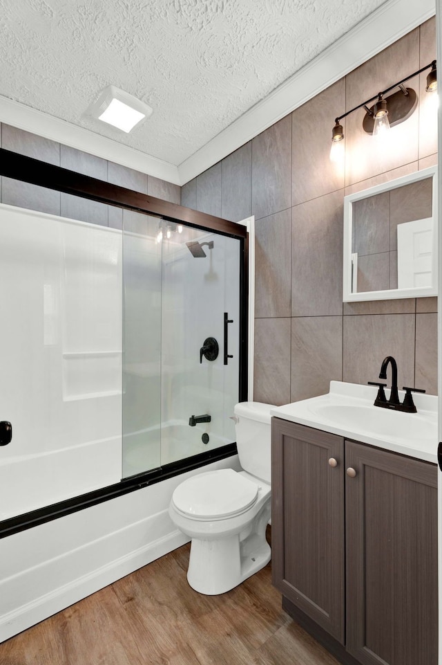 full bathroom with hardwood / wood-style flooring, toilet, enclosed tub / shower combo, tile walls, and a textured ceiling