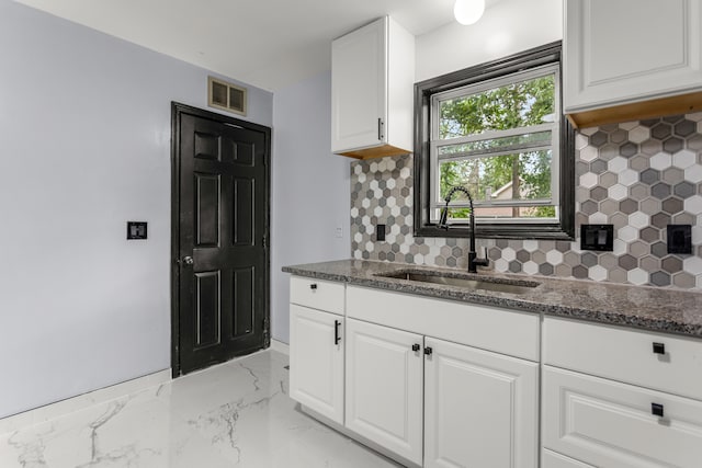 kitchen with white cabinets, backsplash, sink, and dark stone counters