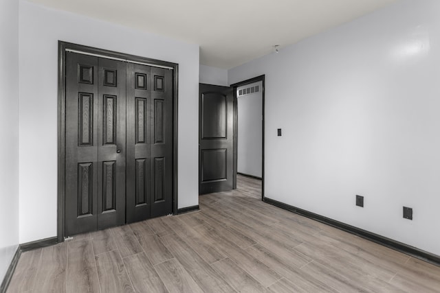 unfurnished bedroom featuring light hardwood / wood-style floors and a closet