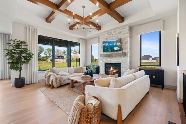 living room with a fireplace, light hardwood / wood-style flooring, a healthy amount of sunlight, and coffered ceiling