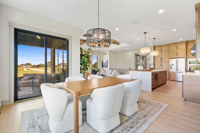 dining space with light hardwood / wood-style flooring, a chandelier, and sink