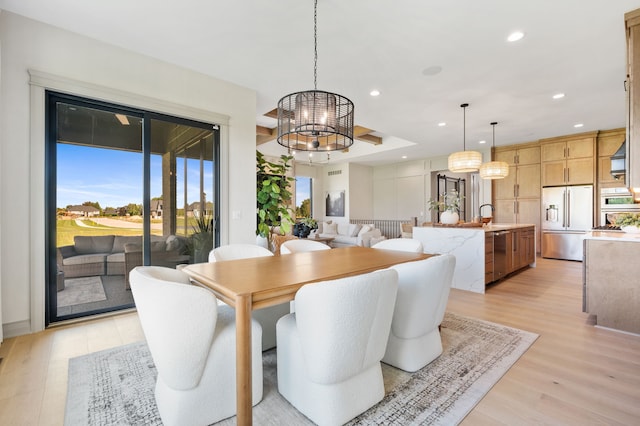 dining area featuring a notable chandelier, light wood-type flooring, and sink