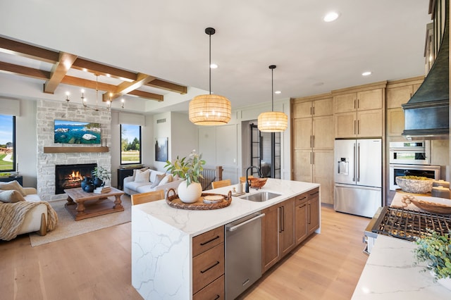 kitchen featuring pendant lighting, sink, light hardwood / wood-style flooring, appliances with stainless steel finishes, and light stone counters