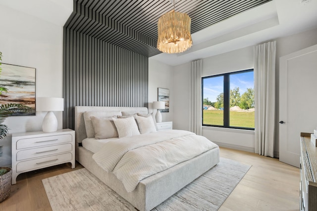 bedroom with a chandelier and light wood-type flooring