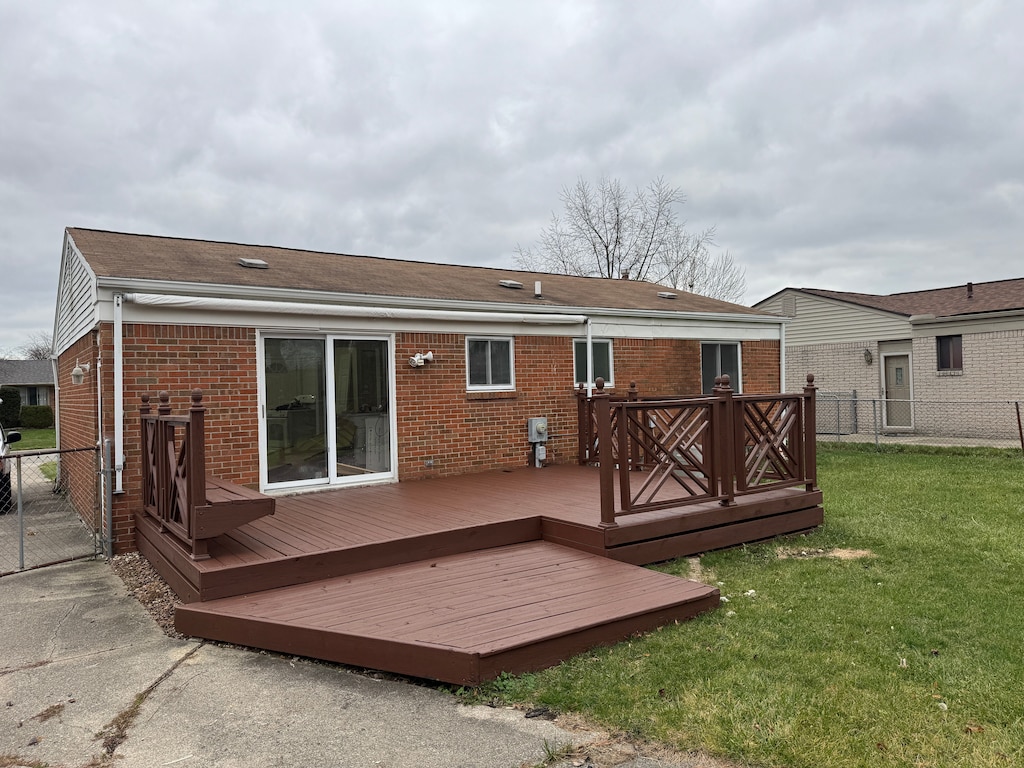 back of property featuring a wooden deck and a yard