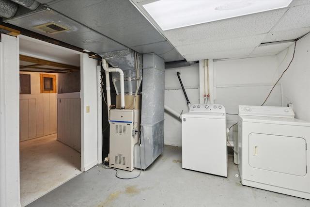 basement featuring washing machine and dryer, a paneled ceiling, and heating unit