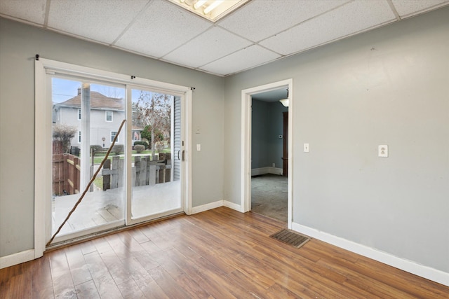 empty room with a drop ceiling and hardwood / wood-style flooring