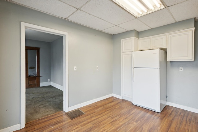 kitchen featuring a paneled ceiling, white cabinets, hardwood / wood-style floors, and white fridge