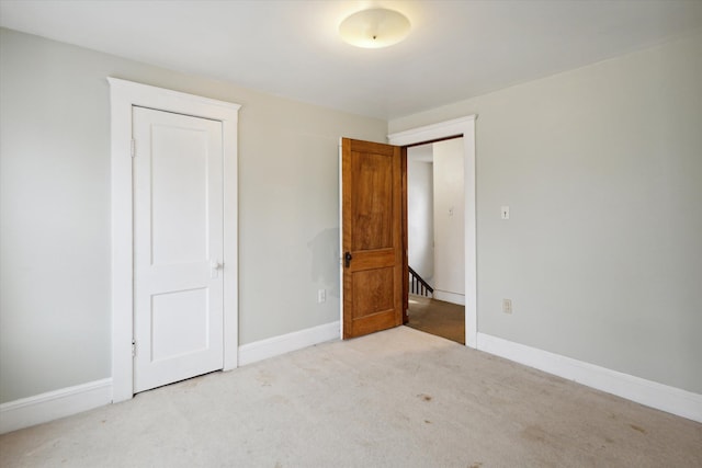 unfurnished bedroom featuring light colored carpet and a closet