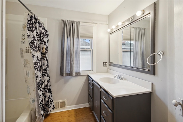 bathroom featuring wood-type flooring, vanity, and shower / tub combo