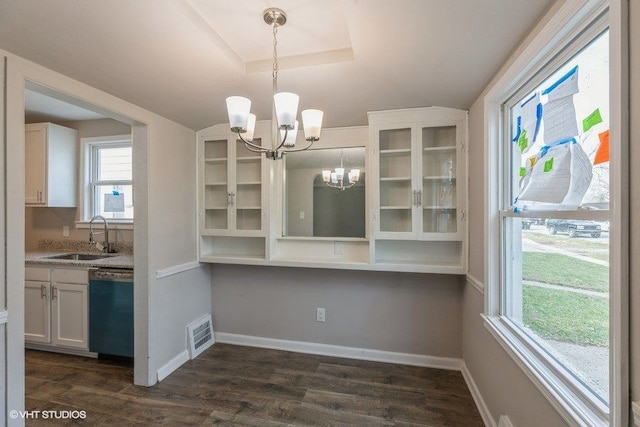 unfurnished dining area with a tray ceiling, sink, dark hardwood / wood-style floors, and a notable chandelier