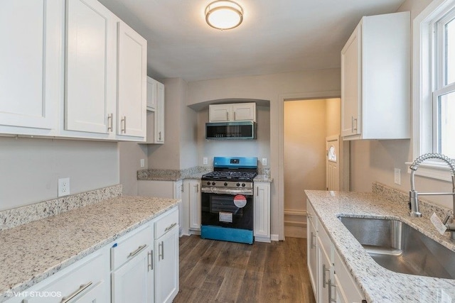 kitchen with light stone countertops, sink, stainless steel appliances, dark hardwood / wood-style floors, and white cabinets