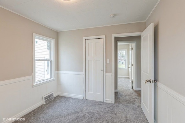 unfurnished bedroom featuring light colored carpet, crown molding, and a closet