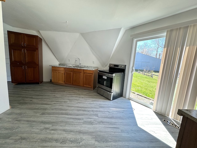 kitchen with light hardwood / wood-style flooring, vaulted ceiling, sink, and stainless steel range with electric stovetop