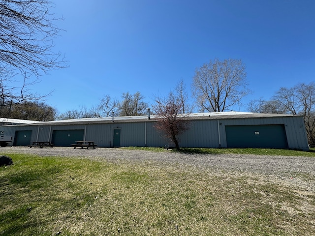 back of property featuring a lawn, an outbuilding, and a garage