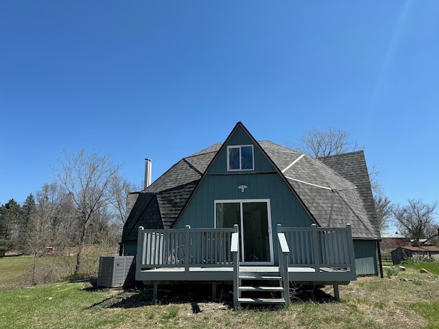 rear view of house featuring a deck, central AC unit, and a lawn