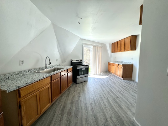 kitchen with light stone countertops, sink, stainless steel electric range oven, vaulted ceiling, and light hardwood / wood-style flooring