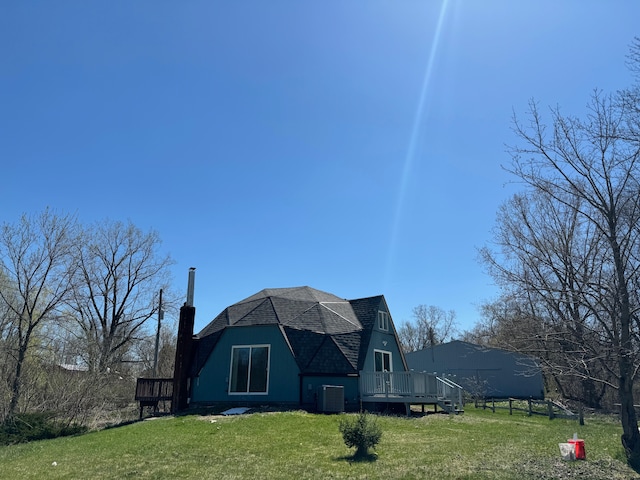 rear view of house featuring central AC unit, a wooden deck, and a lawn