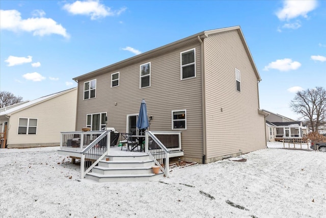 snow covered rear of property featuring a deck