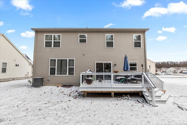 snow covered rear of property featuring a deck and central air condition unit